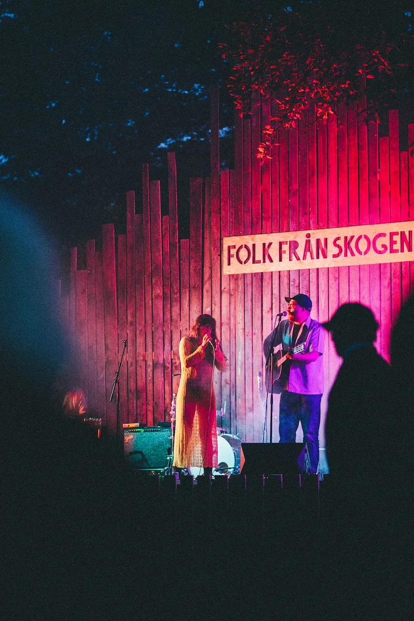 Vilma Flood och gitarrist på ängen med rosa belysning i bakgrunden under folk från skogen 2024